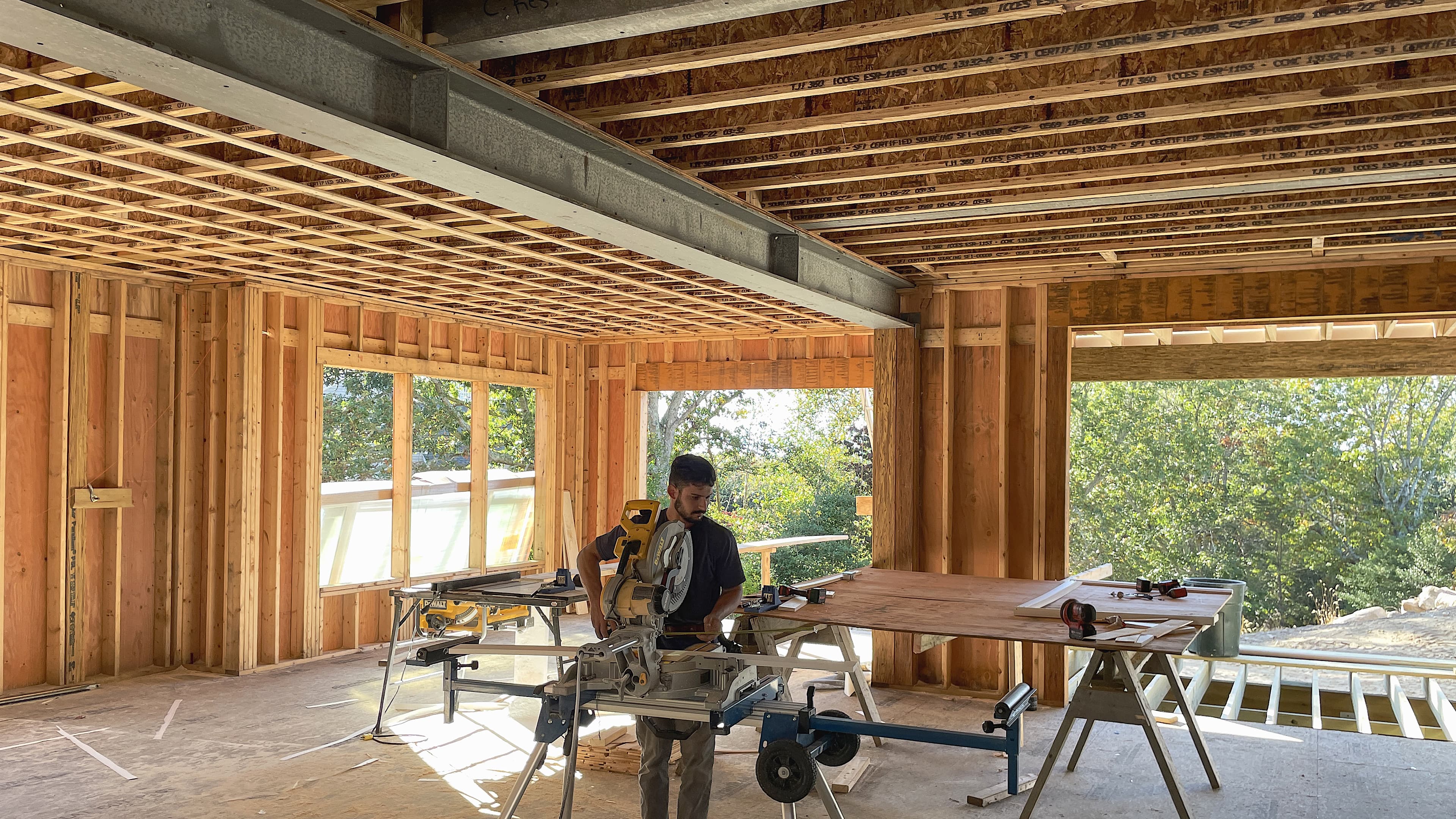 Longfellow carpenter cutting finish work in a newly framed living room